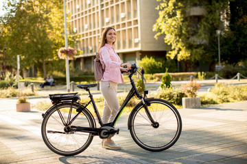 Obraz premium Young woman with modern city electric e-bike clean sustainable urban transportation