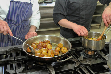 Chefs cook potatoes in a pot in a restaurant kitchen