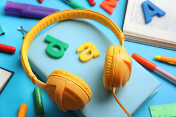 Books, headphones and stationery on light blue background, closeup