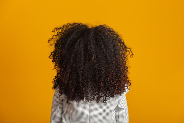 Young black woman on her back with afro hairstyle on yellow background. Girl with african...