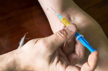 Hand making syringe injection of heroin.