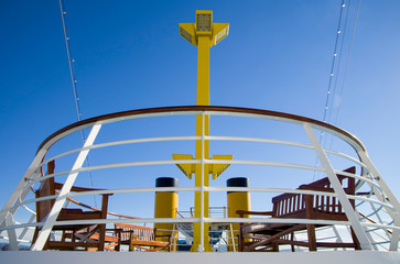 Yellow funnel and outdoor deck of Italian cruise ship or cruiseship liner with blue sky with...