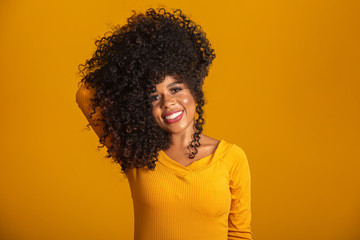 Young afro-american woman with curly hair looking at camera and smiling. Cute afro girl with curly hair smiling looking at camera.