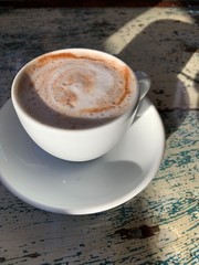 cup of coffee with cream on wooden background