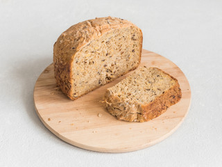 Half a loaf of homemade whole grain bread with various seeds and two slices on a white background. Healthy natural fresh food. Close-up