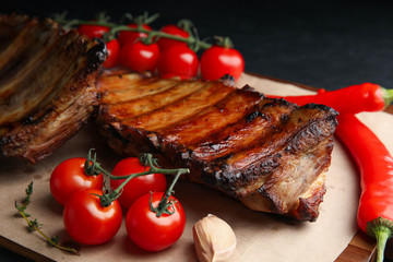 Tasty grilled ribs with tomatoes and peppers on table, closeup