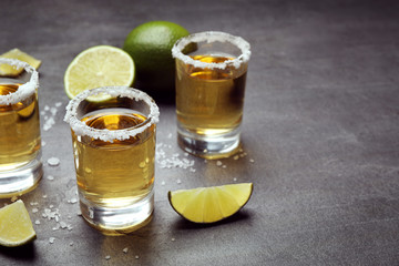 Mexican Tequila shots, lime slices and salt on grey table