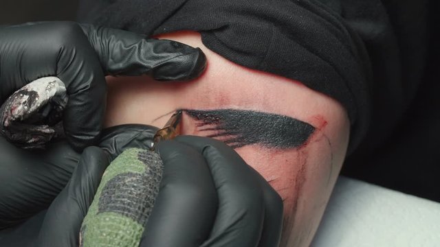 Shooting of man tattooist getting tattoo of snake in salon