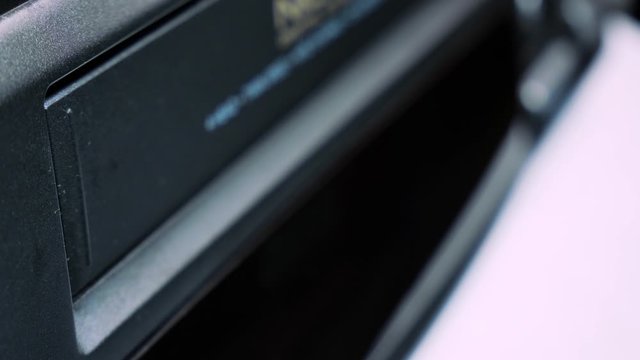 Close-up insert a vintage VHS video cassette tape into the recorder VCR 4k