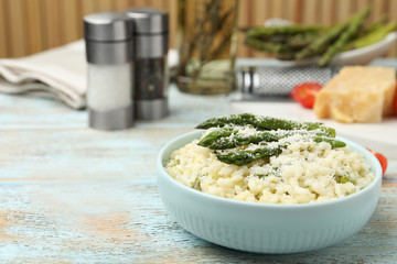 Delicious risotto with asparagus and cheese on wooden table. Space for text