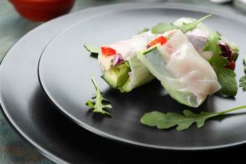 Delicious rolls wrapped in rice paper on light blue wooden table, closeup