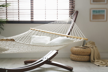 Fototapeta na wymiar Comfortable net hammock with pillows in stylish room. Interior design