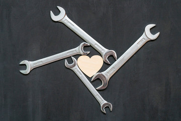 Heart and car tools. Wrenches spanners around heart on black background. Symbol of health....