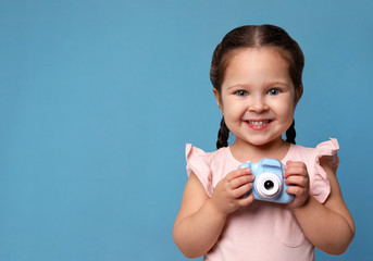 Little photographer with toy camera on light blue background. Space for text