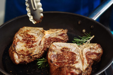 Raw Fresh Marbled Meat Beef on a grill pan ready for cooking. Man cooking beef steaks. Male hands holding a grill pan with beef steaks on kitchen