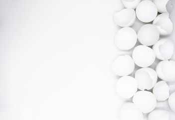 Lots of broken white eggshells on a white background. On the left. Copy space