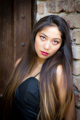 Fototapeta premium Young beautiful woman next to textured stone building.