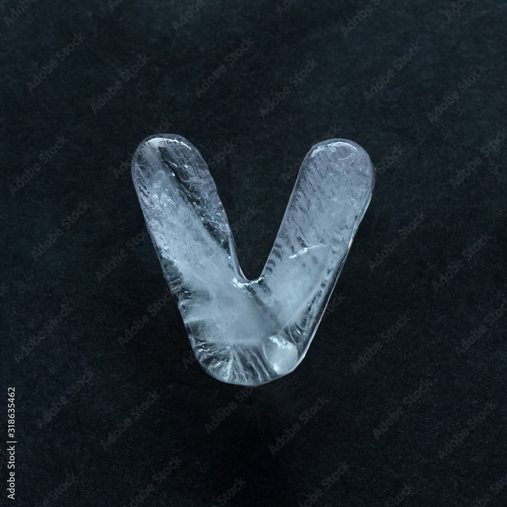 Fototapete melting speech. alphabet's shiny and well-structured letters made out of ice isolated on dark studio