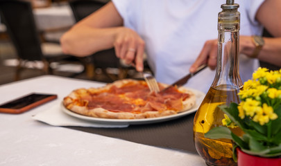 Baked traditional italian pizza on the plate. Girl eating pizza at restaurant. Woman's hands taking of fresh pizza with tomatoes and mushrooms.