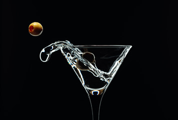Silhouette of martini with green olives on a black background.