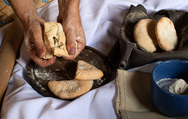 MANOS DE  MUJER PARTIENDO PAN DE CAMPO RECIÉN HORNEADO