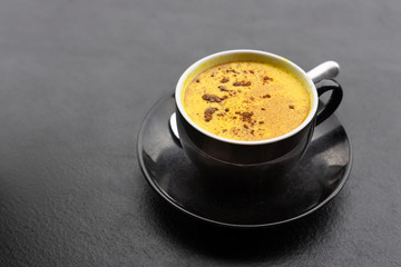 Serving of aromatic turmeric black coffee against dark table