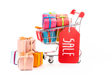 decorative small shopping cart with gift boxes and price tag with sale lettering isolated on white