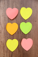Colored hearts stick notes on a wooden surface
