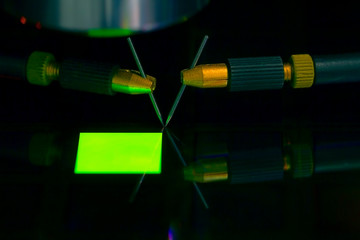 Close up of examining a sample of OLED display with probe station under the microscope in laboratory.A semiconductor on a silicon wafer. Selective focus.