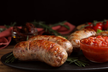 Tasty grilled sausages served with sauce on wooden table