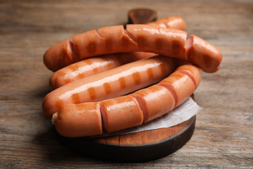 Delicious grilled sausages on wooden table, closeup