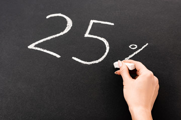 cropped view of woman holding chalk near number 25 and percent sign written on chalkboard