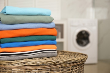 Stack of fresh laundry on basket in bathroom. Space for text