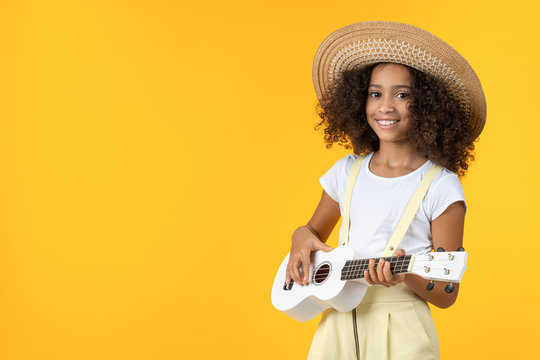 Little girl in hat playing ukulele isolated on white background