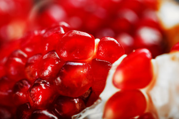 Red ripe and juicy seeds of fresh pomegranate fruit close-up.