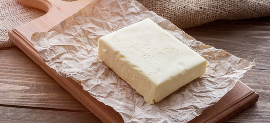 Wooden board with cut block of butter.Knife on a rustic table and butter