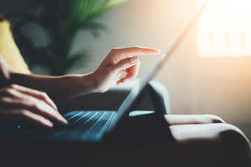 Female freelancer businesswoman working from home via modern portable computer device, young hipster girl using digital tablet while working at loft studio, flare light on the background