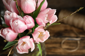 Beautiful bouquet with spring pink tulips on table, above view