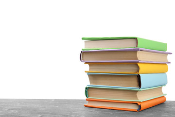Stack of colorful books on grey stone table against white background