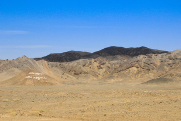 Fototapeta na wymiar Desert landscape with rocks and geological formations on a hot summer day on the road from Kerman to Mashhad.