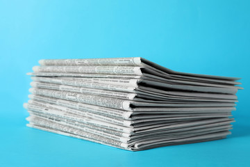 Stack of newspapers on light blue background. Journalist's work