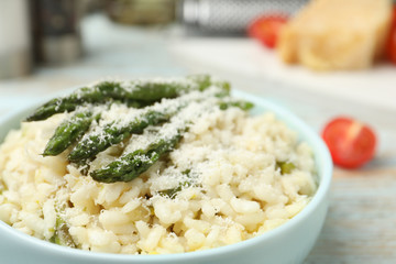 Delicious risotto with asparagus and cheese in bowl, closeup