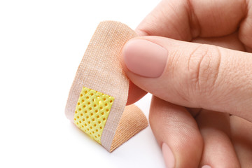 Woman putting sticking plaster on white background, closeup. First aid item