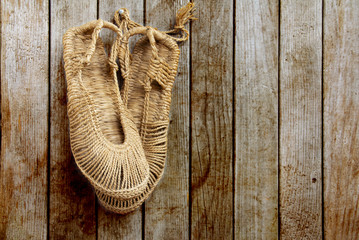 Vintage Chinese straw shoes on grunge wooden wall