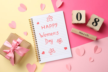 Copybook with inscription Happy women's day on decorated background, top view