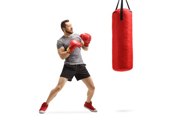 Young man exercising box with a red punching bag