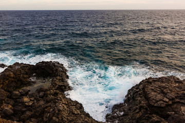 ocean waves hit and crash against stones