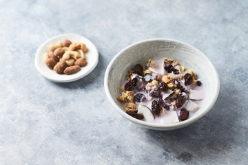 Bowl of granola with yogurt, nuts, cranberry and cocoanut. Concept for a tasty and healthy meal. Stone  background. 