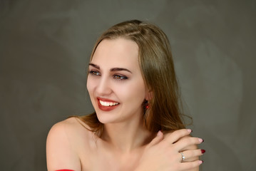 Fototapeta premium Cosmetics concept, facial skin care. A close-up portrait of a pretty Caucasian model with excellent facial skin and good makeup on a gray background.