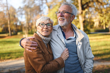 Smiling senior couple walking in the park together enjoying retirement
